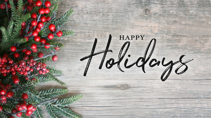 Wall Mural - happy holidays text with holiday evergreen branches and berries over rustic wooden background