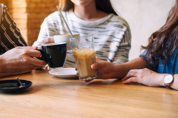 Wall Mural - Closeup image of three people enjoyed talking and drinking coffee together in cafe