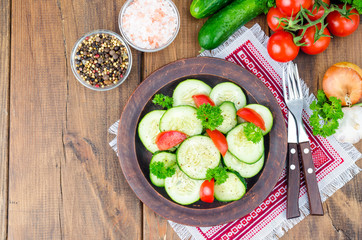 Wall Mural - Diet salad of fresh cucumbers and tomatoes, cut into slices on wooden table