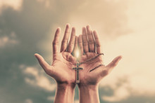 Praying Hands Hold A Crucifix Or Cross Of Metal Necklace With Faith In Religion And Belief In God On Confession Background. Power Of Hope Or Love And Devotion.