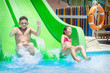 © tsomka - Summer bright sunny at the water park brother and sister with slide down the hill/