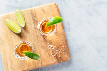 Wall Mural - Golden tequila shots with lime slices and salt, shot from above with a place for text