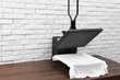 Heat press machine with t-shirt on wooden table near white brick wall. Space for text