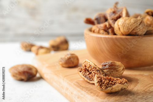 Fotomural Wooden board with tasty dried figs on light table. Space for text