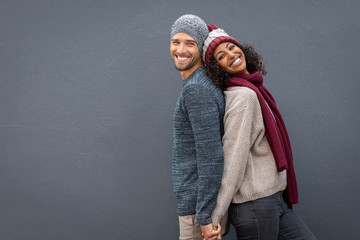 Wall Mural - Happy couple in winter clothes leaning against back