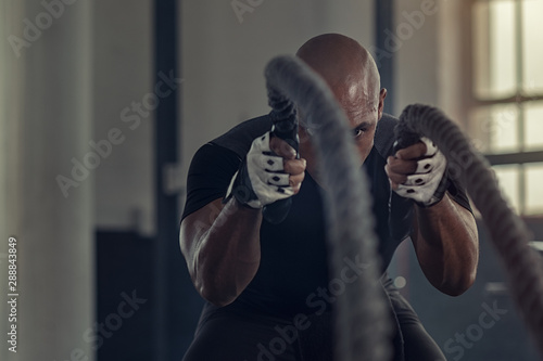 Cuadros en Lienzo Black man doing intensive battle rope workout