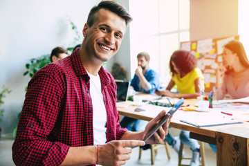 Wall Mural - Modern beautiful confident young business man in smart casual wear   stands in front of successful business team that working with graphs and documents