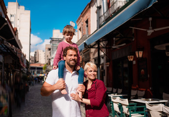 Wall Mural - Young family with small daughter standing outdoors in town on holiday.