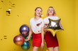 © Вячеслав Косько - Two happy beautiful woman friend celebrating posing surrounded by colorful air balloon confetti. Attractive smiling female wearing bright clothes enjoying party isolated at yellow studio background