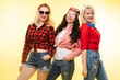 © Вячеслав Косько - Studio shot of trendy girls with head bows, sunglasses wearing trendy hipster clothes and smiling at camera. Isolate on yellow background.