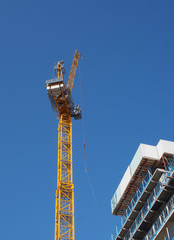 Wall Mural - a view of a tall tower crane working on large construction sites against a blue sky