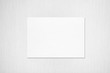 Empty white horizontal rectangle poster mockup with soft shadow on neutral light grey textured background. Flat lay, top view