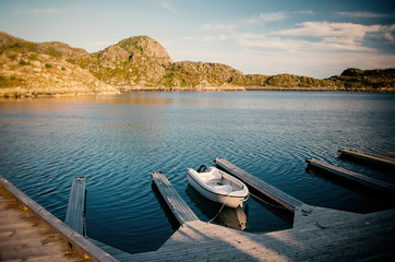 Naklejka na meble Small white boat on a wooden pier on the shore, Lofoten Islands Norway