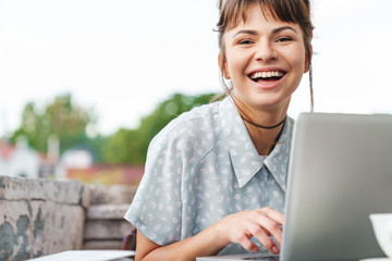 Canvas Print - Emotional happy young beautiful woman using laptop computer on a balcony.