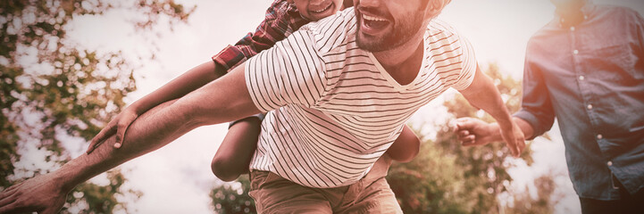 Happy grandfather looking at man giving piggy backing to son