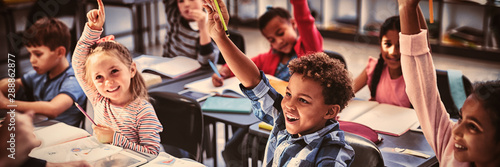 Fotomural Schoolkids raising their hands in classroom