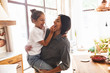 © Drobot Dean - Image of amusing family mother smiling and holding her little daughter in hands at cozy apartment