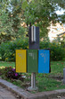 Metal recycle bins for different types of rubbish in the park. Concept of waste sorting and clean environment.