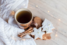 Christmas Gingerbread Glazed Cookies, Mug Of Tea, Cinnamon At Wooden Background With Glares. Cozy Tea Time With Homemade Sweets And Cup Of Hot Beverage. Winter Food, Drink, New Year Lights