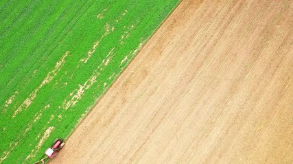 Wall Mural - Tractor with plough working on a field. Farmer use green manure for organic growing.  Agriculture from above. Environmentally friendly farming.