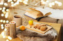 Hygge And Cozy Home Concept - Oatmeal Cookies, Lemon Tea And Candles On Wooden Table In Living Room