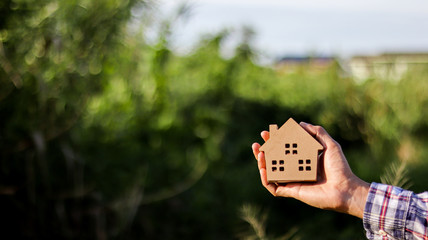 Wall Mural - Small wooden toy house in men hands.