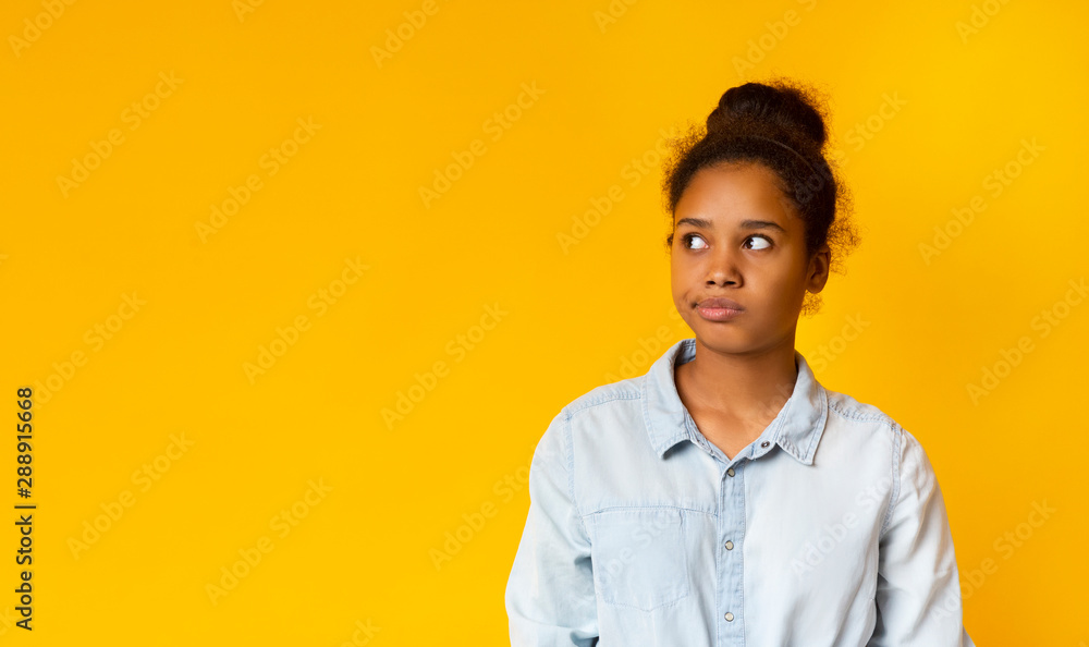 Annoyed african girl looking aside at free space - obrazy, fototapety, plakaty 