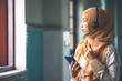 © rachaphak - Portrait of a smiling young modern arabian woman holding mobile phone and listening the music to headphone.