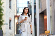 © Syda Productions - lifestyle and people concept - happy smiling young asian woman with takeaway coffee cup walking along city street