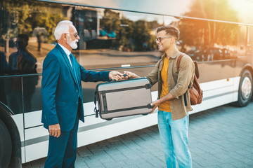 The bus driver accepts luggage from passenger.