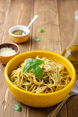 Wall Mural - Spaghetti pasta with sauce pesto and parmesan cheese in ceramic bowl on wooden table
