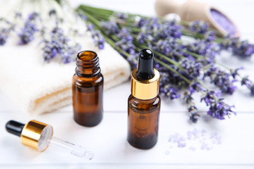 Wall Mural - Lavender oil in bottles with flowers and towel on white wooden table