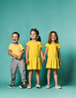 © FAB.1 - Studio portrait of children on a light background: full body shot of three children in bright clothes, two girls and one boy. Triplets, brother and sisters.