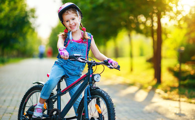 Wall Mural - happy cheerful child girl riding a bike in Park in nature