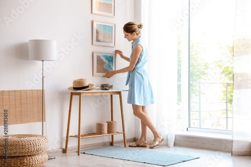 Fotografía Female interior designer decorating white wall with pictures indoors