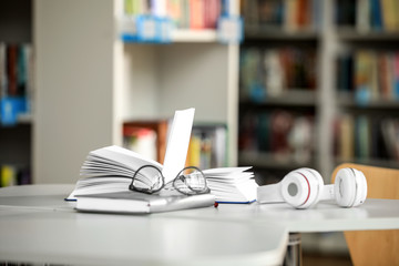 Wall Mural - Books, glasses and headphones on table in library