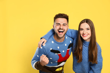 Wall Mural - Couple wearing Christmas sweaters on yellow background