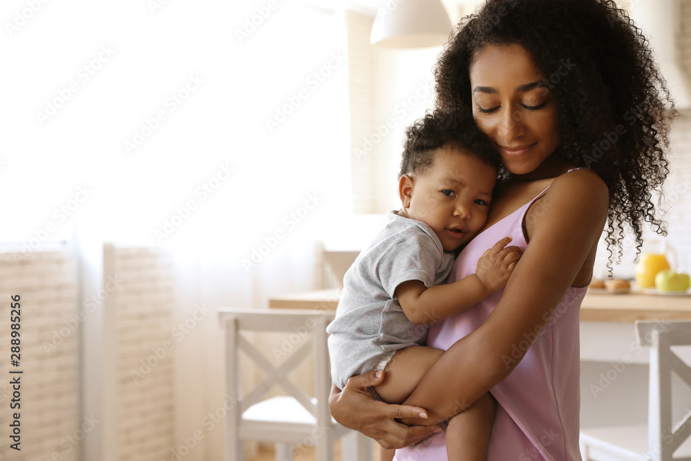 African-American woman with her baby in kitchen. Happiness of motherhood - obrazy, fototapety, plakaty 
