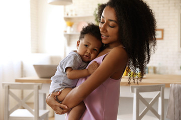 Canvas Print - African-American woman with her baby in kitchen. Happiness of motherhood