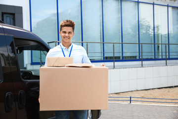 Poster - Young courier holding parcels near delivery car outdoors. Space for text