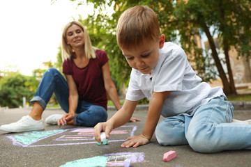 Sticker - Nanny with cute little boy drawing house with chalks on asphalt