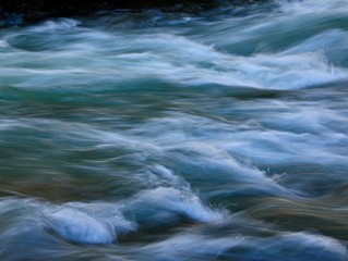 waves and ripples from a mountain stream are rendered with a slow shutter speed to give a smooth, silky feel to the photograph