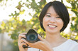 © Kenishirotie - Portrait young Asian woman outdoor with a digital camera smiling
