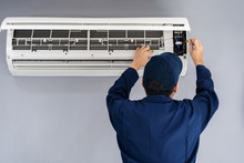 Electrician With Screwdriver Repairing Air Conditioner Indoors