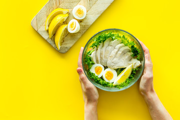 Wall Mural - Healthy dinner in bowl in hands on yellow background top view