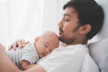 Asian Cute Baby Boy Sleeping On Father's Chest In The Bedroom
