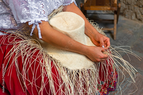 Fotografía Woman weaving a Panama hat, also known as the traditional brimmed straw hat made of the Toquilla palm, which is on the Unesco Intangible Cultural list and famous from the city of Cuenca, Ecuador