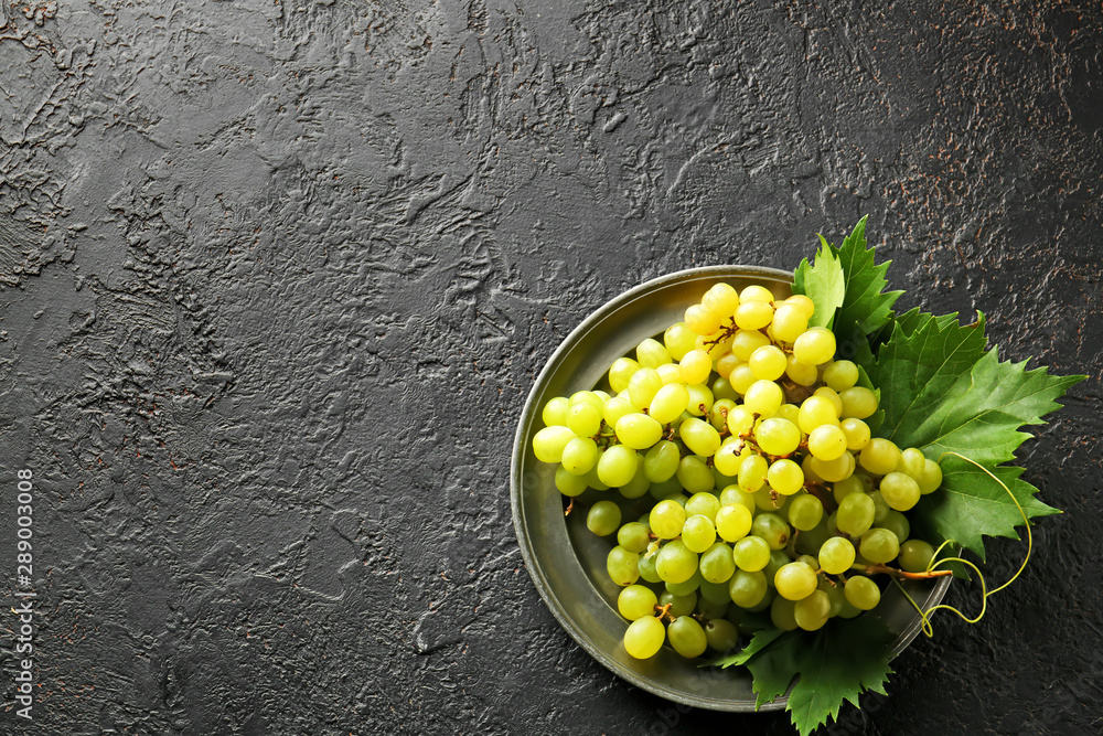 Plate with ripe sweet grapes on dark background
