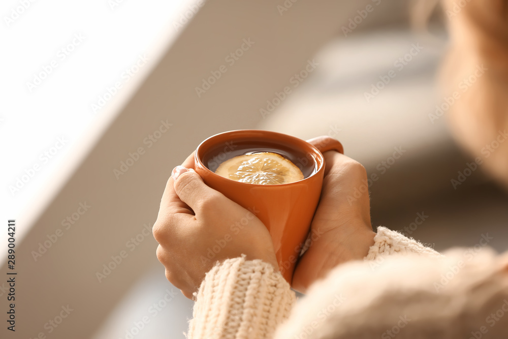 Young woman drinking hot tea at home, closeup
