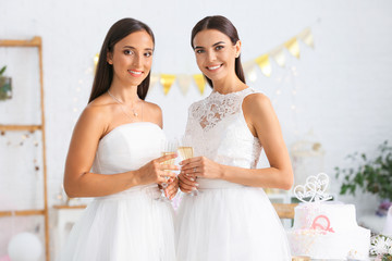 Wall Mural - Beautiful lesbian couple with glasses of champagne during wedding ceremony